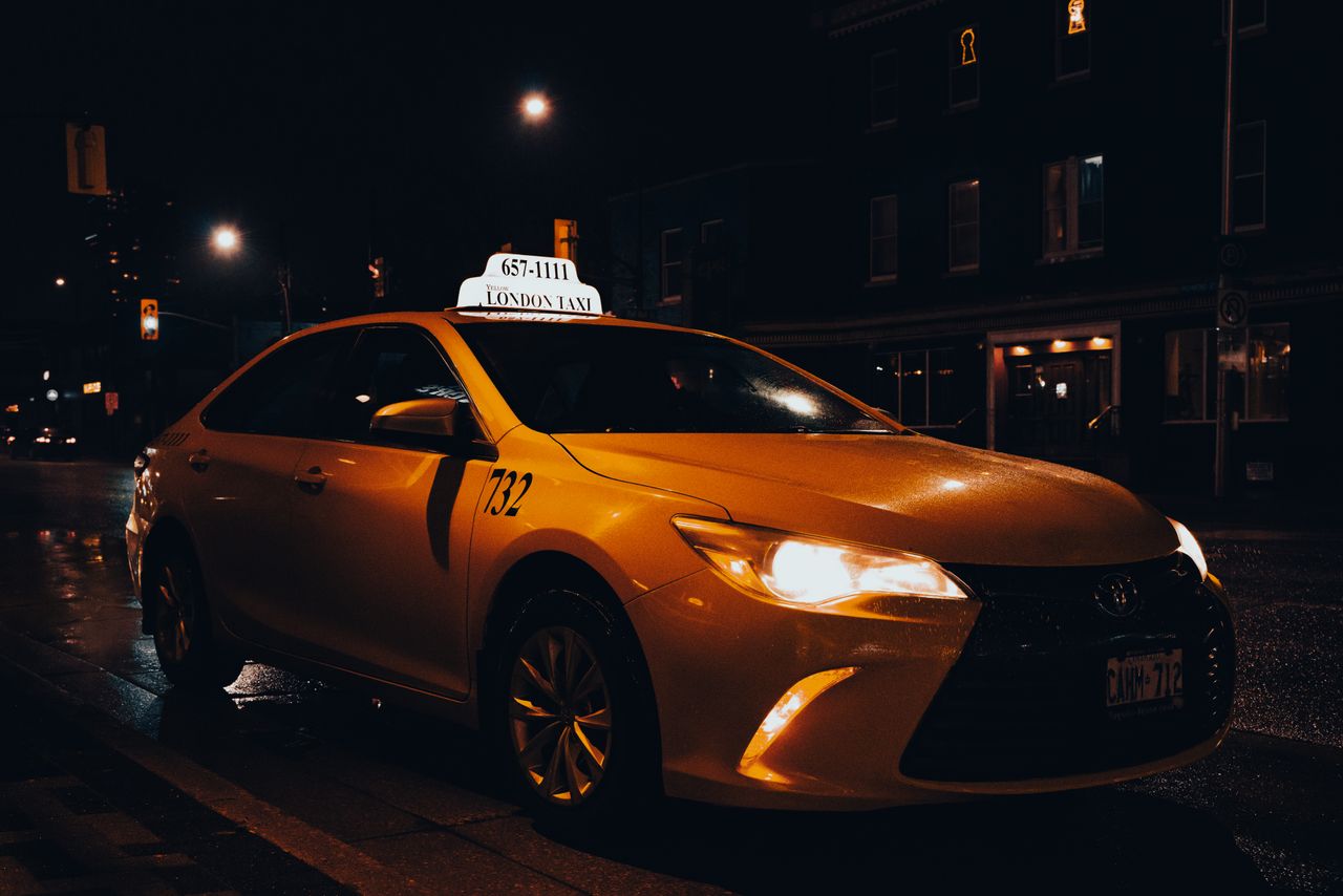 services-03 A yellow taxi waiting at night in London, Ontario, Canada. Urban transportation captured with street lights.