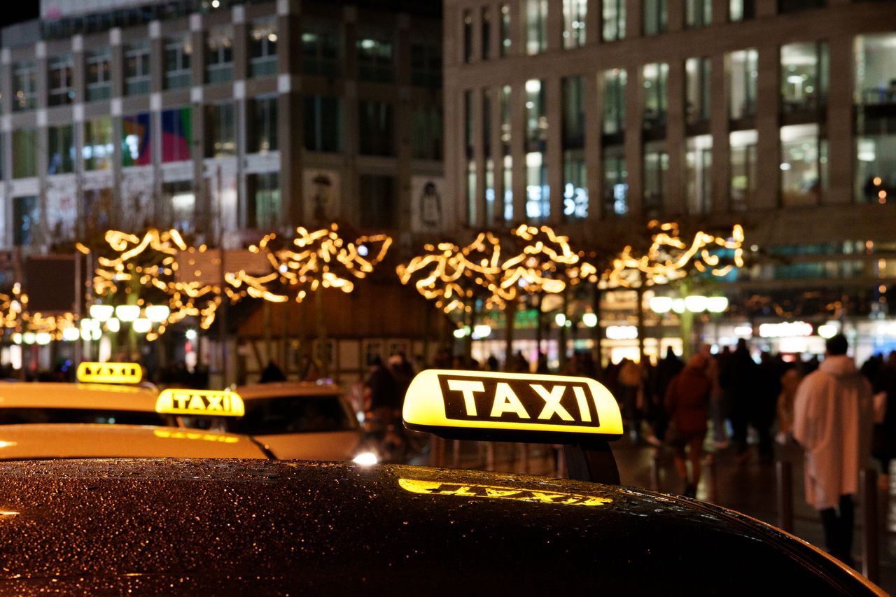services-01 A vibrant city scene at night featuring taxis with illuminated signs and festive decorations.