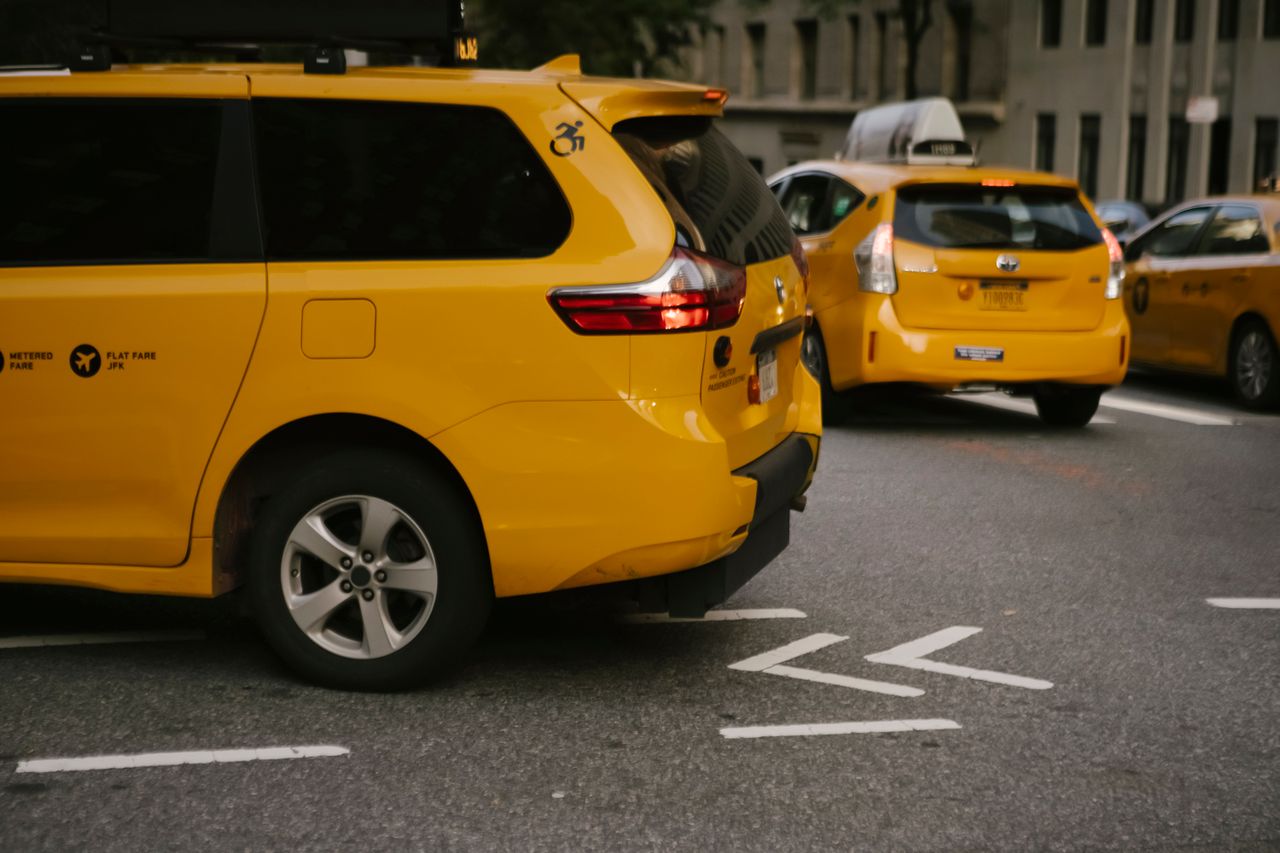 services-02 Modern yellow crossover taxi cars riding on asphalt road near commercial buildings in city